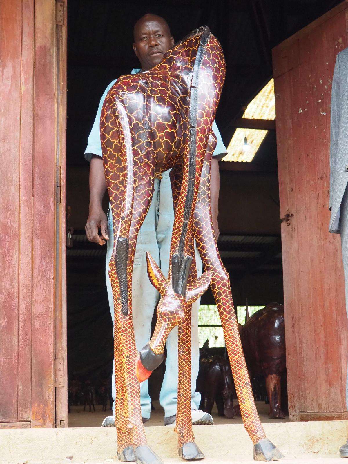The same giraffe held upright in the doorway of a carving shed