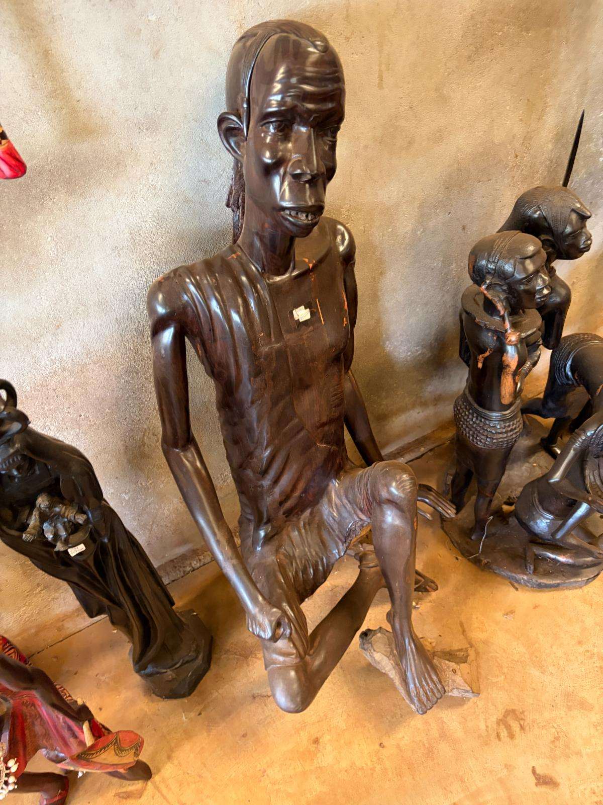 A large seated human figure carved in dark hardwood